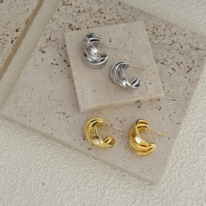 Close-up of geometric multi-layer C-shaped earrings in polished gold and silver finishes