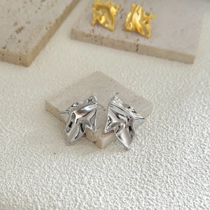 Detailed view of silver and gold irregular fluid metal earrings on stone texture