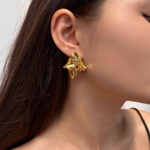 Irregular liquid metal fold earrings in gold finish worn by model in close-up view