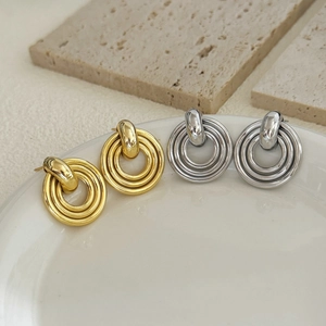 Modern 18K gold and silver layered disk drop earrings displayed on a ceramic tray