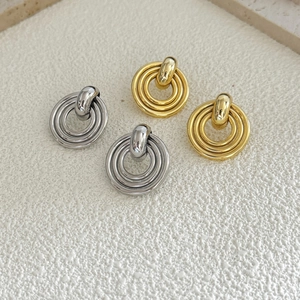 Close-up of geometric 18K gold and silver triple disc earrings on stone surface