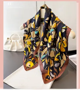 Détail de l'écharpe satinée avec motifs floraux jaunes et bordure marron contrastée