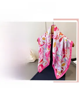 Détail d'un foulard en soie à imprimé floral rose et jaune sur un cintre doré élégant
