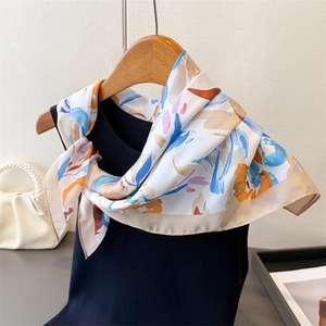 Gros plan d'un foulard en soie aux motifs abstraits colorés suspendu sur un cintre en bois