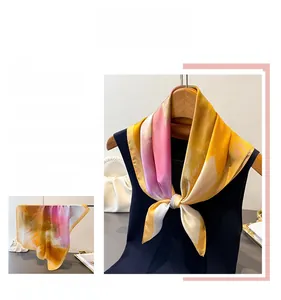 Detail eines Satin-Halstuchs mit gelb-rosa abstraktem Print auf einem Kleiderbügel