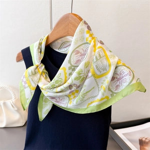 Detail of printed silk scarf tied on a dark top featuring sardine and floral patterns