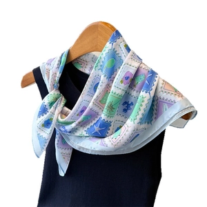 Elegant floral print silk scarf with ocean elements hanging on a wooden hanger
