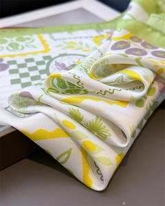 Detailed view of silk scarf fabric showing green plant prints and smooth texture