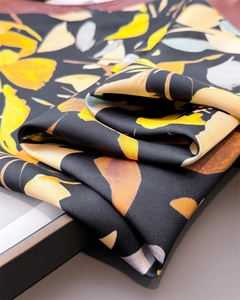 Vue détaillée du tissu en soie avec motifs floraux jaunes et paisley sur fond noir