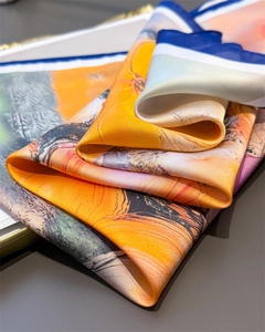 Détail d'un foulard en soie style peinture à l'huile aux tons orange et bordure bleu marine