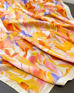 Macro detail of abstract floral printed silk scarf showing satin luster and draped fabric