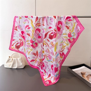 Détail d'un foulard en soie rose avec motif floral et texture de tissu fluide