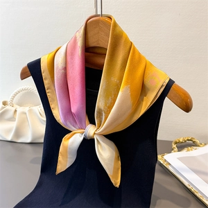 Detailansicht eines Seidenschals mit gelb-rosa Farbverlauf auf Strickpullover