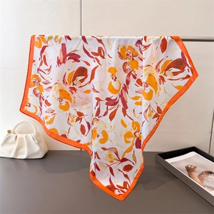 Détail d'un foulard en soie vintage aux tons orange chaud et texture soyeuse brillante