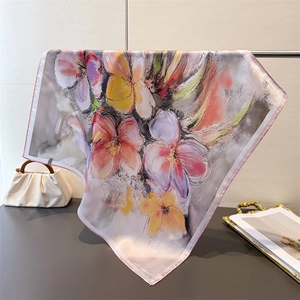 Détail d'un foulard en soie à fleurs avec bords roulés sur un plateau décoratif