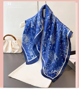 Détail d'un foulard en soie bleue avec motif paisley drapé sur un présentoir blanc élégant