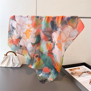 Detailed view of dragonfly and lotus print silk scarf hanging with smooth texture