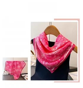 Détail d'un carré de soie rose à motif paisley suspendu sur un cintre en bois