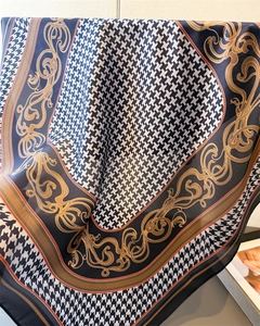 Detailed view of houndstooth and golden baroque patterns on a silk square scarf