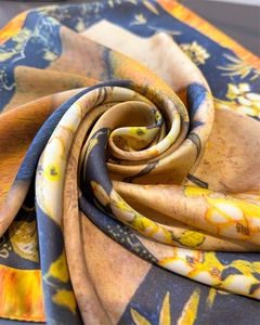 Detailed view of luxury silk scarf with orange tropical floral print and hand-rolled edges