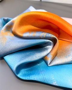 Detailaufnahme von Seidenquadrat-Schal mit orange-blauen abstrakten Farbverläufen