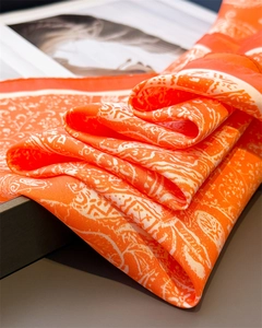Détail macro d'un foulard en soie orange vif avec des motifs paisley blancs élégants