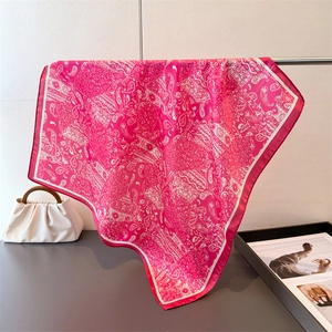 Détail d'un foulard en soie magenta avec motif paisley et texture satinée souple