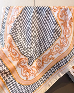 Detail of houndstooth silk scarf showing elegant orange baroque patterns and texture
