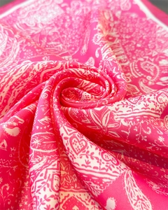 Vue macro d'un foulard en soie rose fuchsia à motifs paisley avec texture satinée