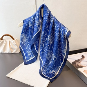 Foulard en soie bleu marine à motifs paisley porté sur un haut en maille blanc