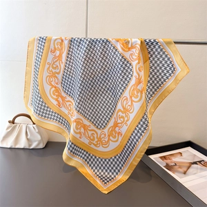 Close-up of houndstooth silk scarf with gold baroque floral borders and elegant drape