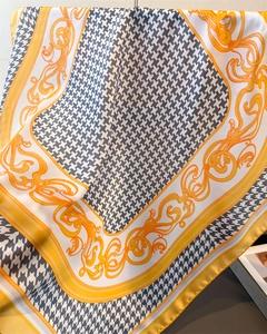 Detailed view of houndstooth silk scarf with baroque patterns in orange and gold