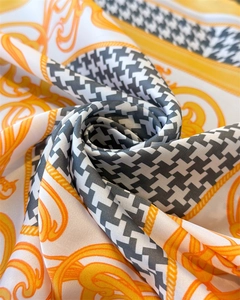 Detailed view of houndstooth silk scarf with yellow chain pattern and smooth fabric texture