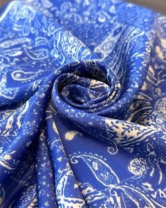 Détail d'un foulard en soie bleu à motif cachemire plié en rose avec éclat soyeux