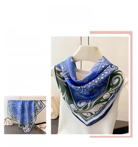 Close-up of royal blue paisley silk scarf showing elegant floral patterns and hemmed edges