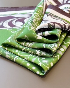 Detailed view of green silk scarf showing paisley patterns and soft satin texture