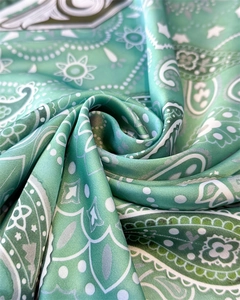 Macro detail of silk paisley pattern scarf showing mint green satin texture and drape