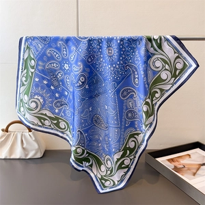 Close-up of royal blue paisley silk scarf with glossy texture and floral border details
