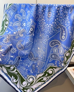 Close-up of bright blue silk scarf with white paisley patterns and green borders