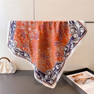 Close-up of luxury paisley and mandala print orange silk scarf with detailed border