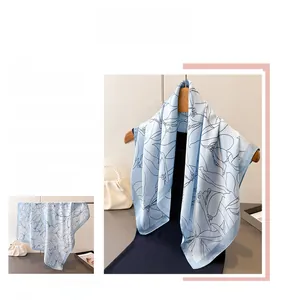 Close-up of silk scarf featuring abstract black floral prints on light blue and white silk