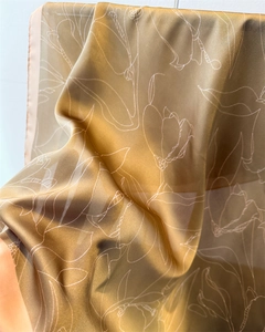 Detail of champagne gold silk scarf showing elegant floral lines and silky draped texture