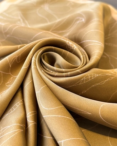 Detail macro shot showing golden brown satin fabric with elegant white floral print patterns