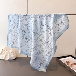 Detailed close-up of light blue silk scarf with delicate black floral line art patterns