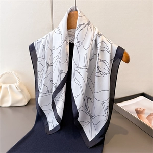 Elegant white silk square scarf with black floral line art and border on a hanger