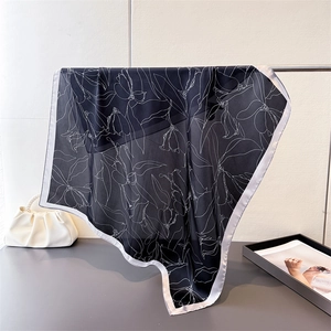 Close-up of black silk scarf with white floral patterns and contrasting borders