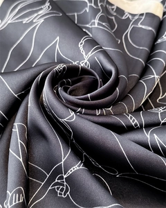 Detailed view of black satin silk scarf with white floral line art print and soft texture