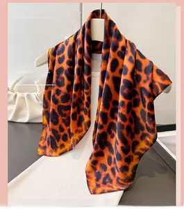 Detail of leopard print silk-like scarf draped over a white hanger and knit top