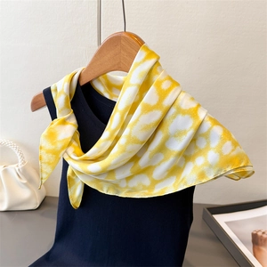 Close-up of a leopard print silk scarf tied on a vest with elegant fashion accessories