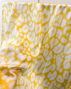 Detailed macro view of yellow leopard print silk scarf with neat hemmed edges and satin finish